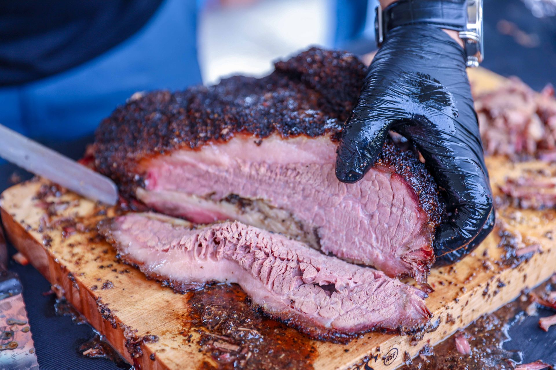 Slicing a smoked beef brisket with a deep black bark
