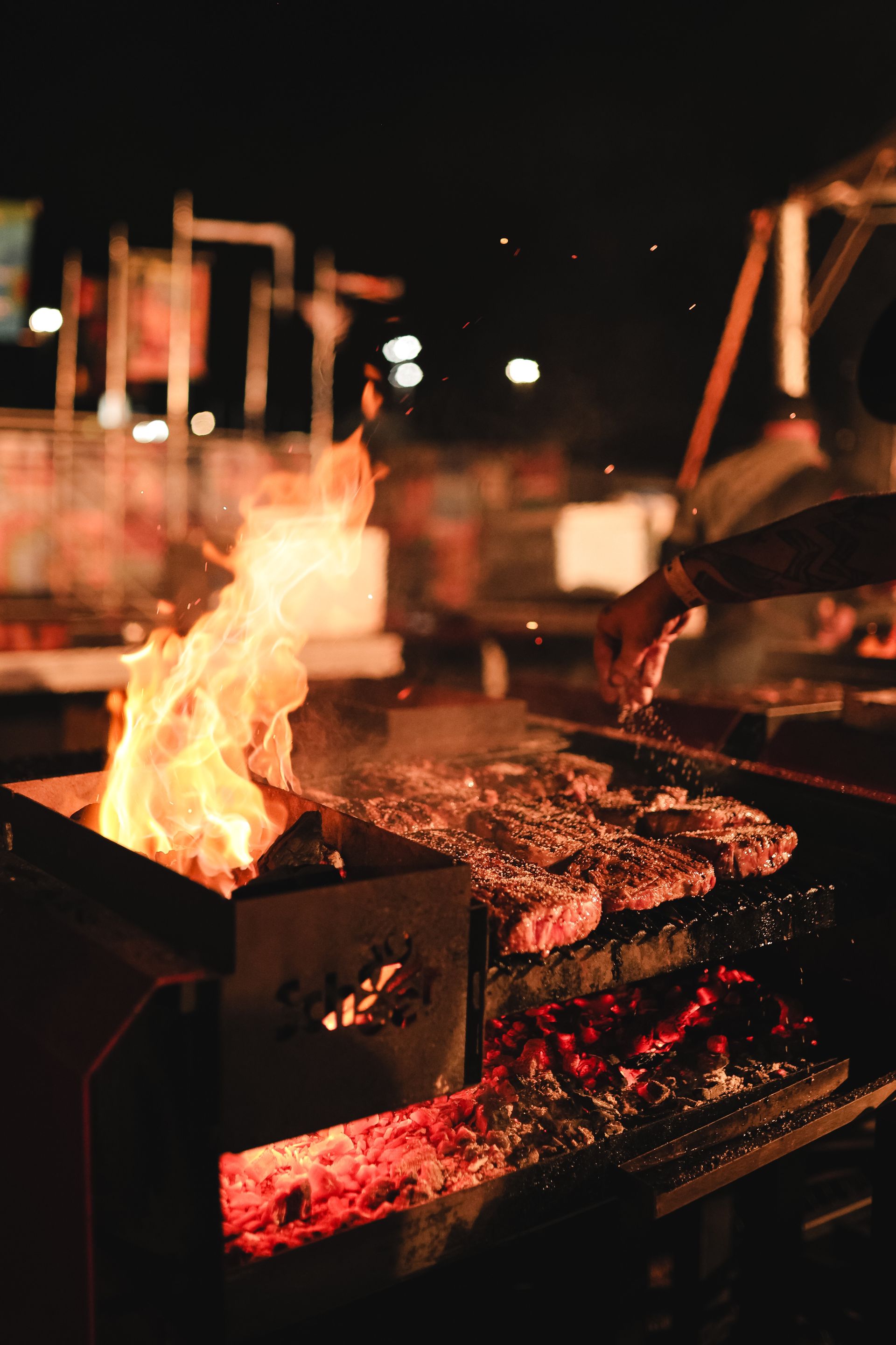 Meat searing over open flame on the grill at night